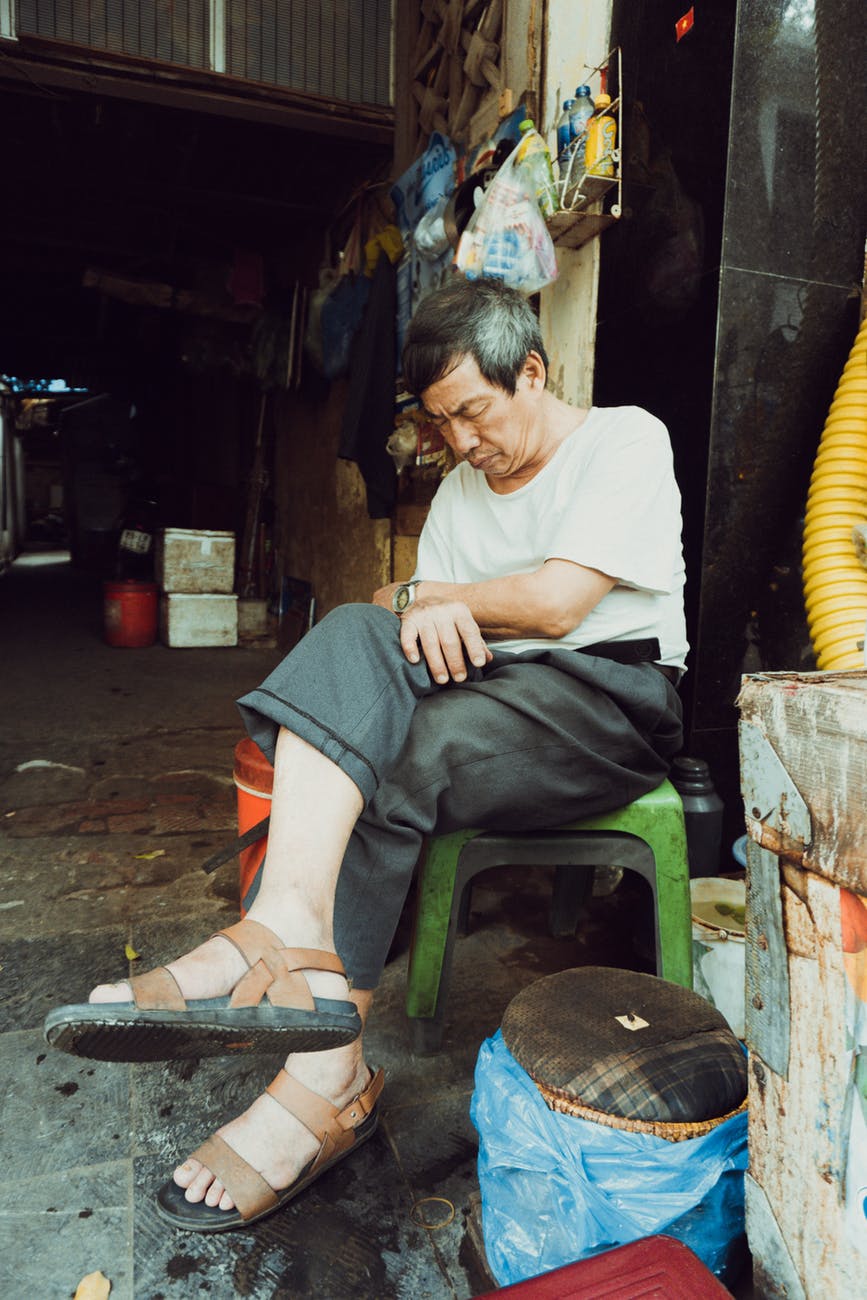 man wearing white shirt and gray dress pants sitting on green stool