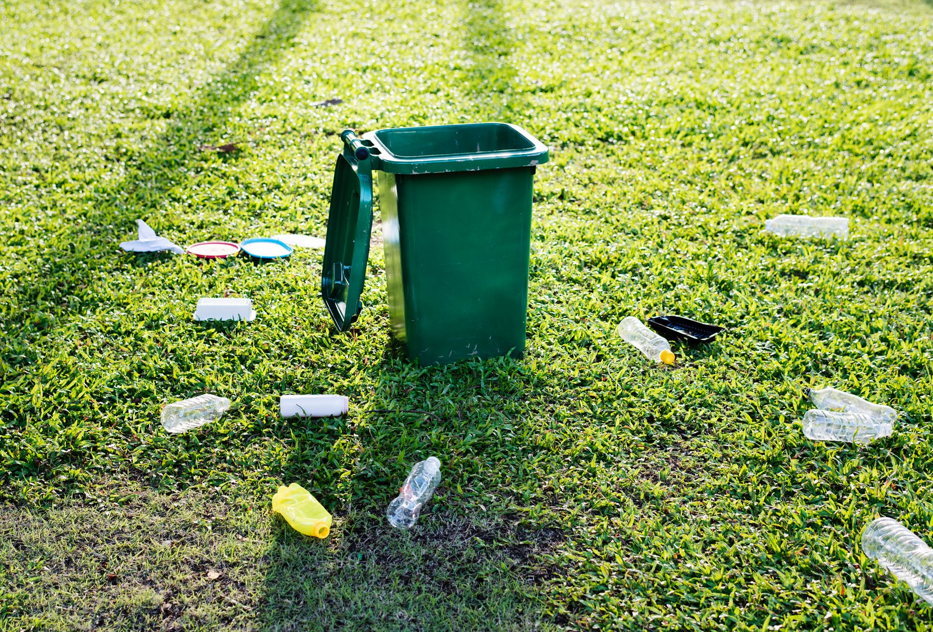 green trash bin on green grass field