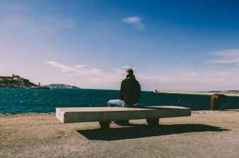 person wearing blue jeans sitting on bench