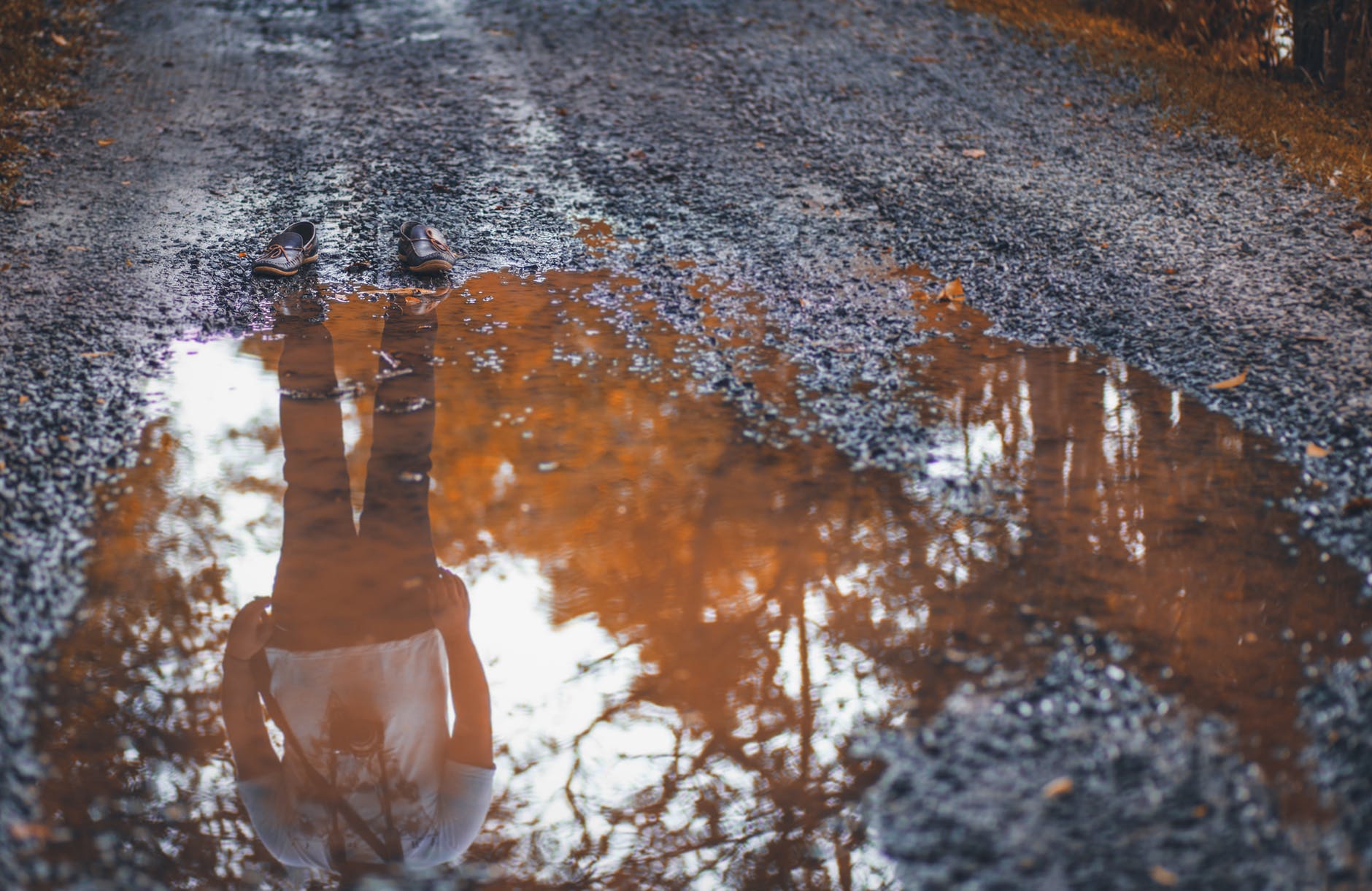 reflection photo of man standing on dirt road
