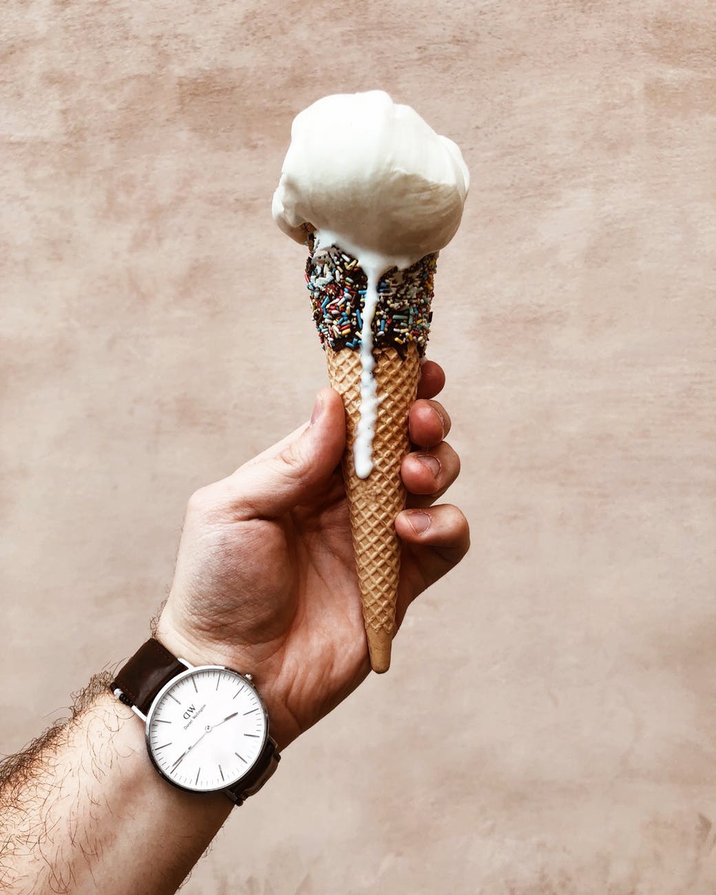 close up photo of man holding melting ice cream cone
