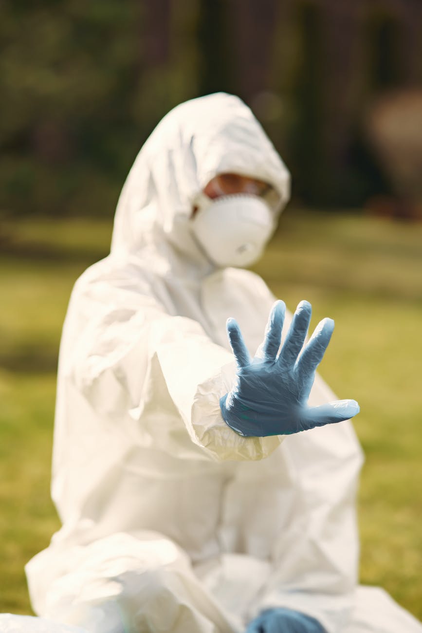 person in white protective suit sitting on green grass field